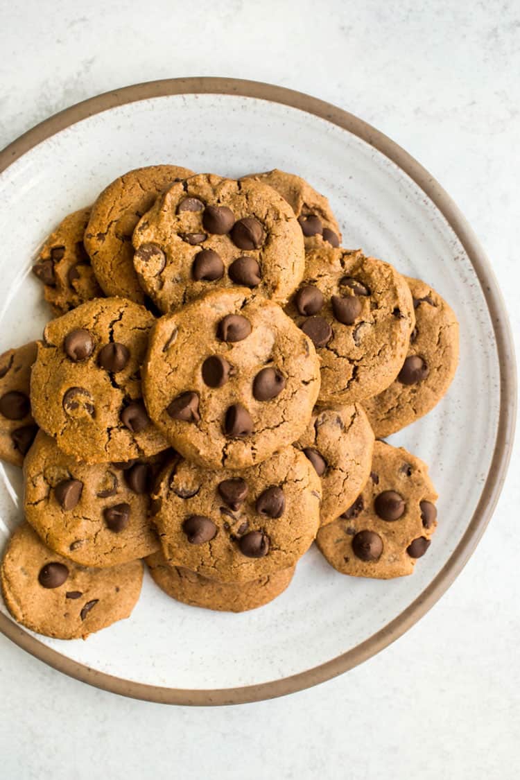 White plate with tan rim filled with chocolate chip cookies