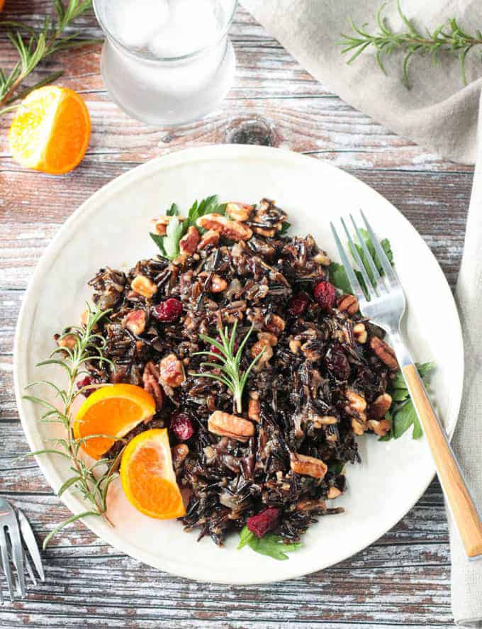 White plate filled with wild rice salad mixed with cranberries and pecans