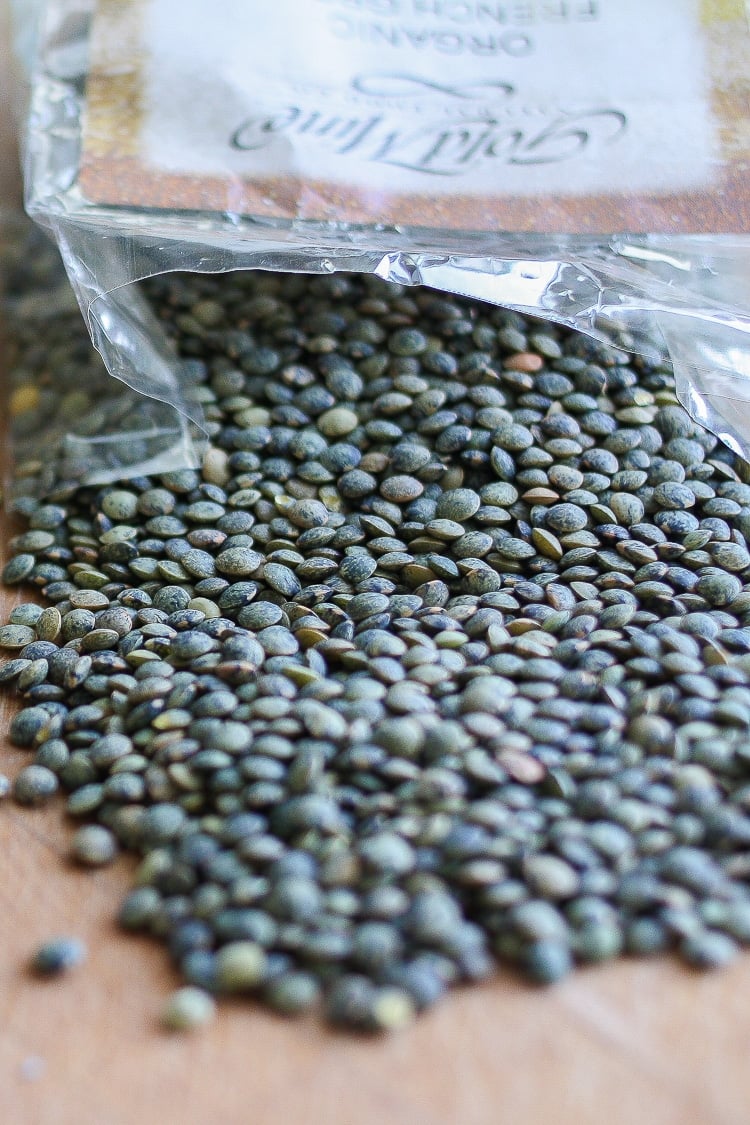 Bag of lentils spilling out onto wooden table top