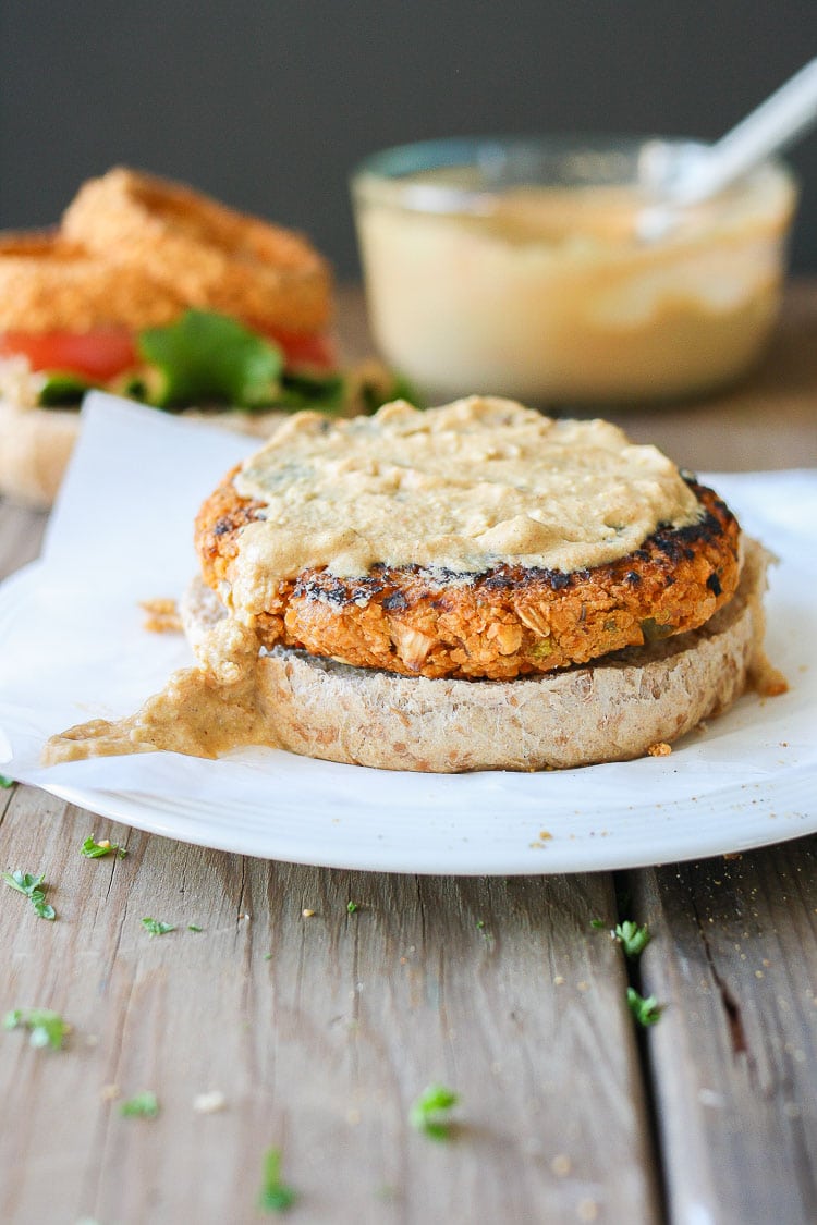 A close up of a chickpea burger patty on a bun and topped with a vegan sauce