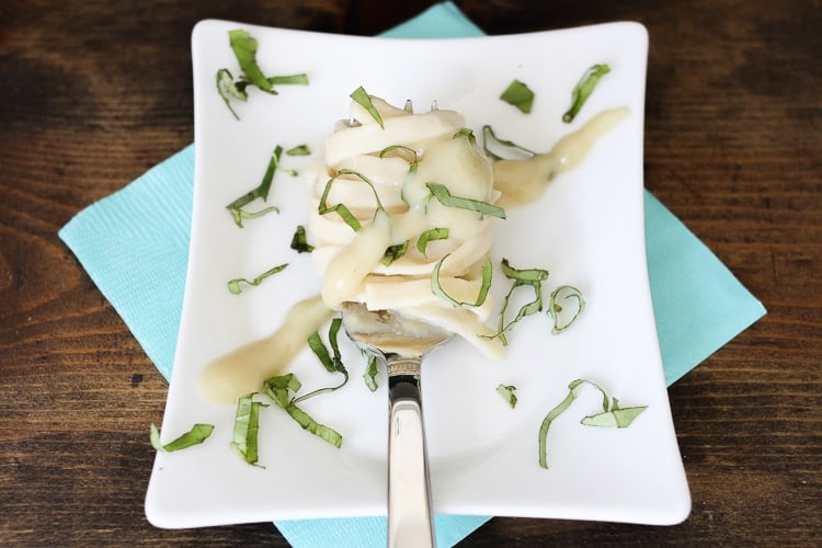 tagliatelle with garlic alfredo sauce on a white plate garnished with basil