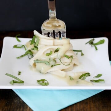 A fork twisting some tagliatelle on a plate with garlic alfredo sauce