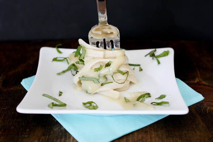 A fork twisting some tagliatelle on a plate with garlic alfredo sauce 