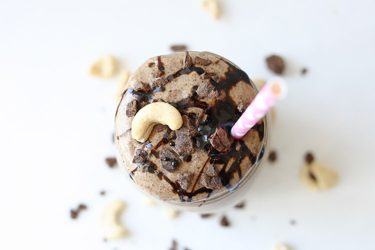 An overhead shot of a Salted caramel smoothie with a straw and topped with cashews