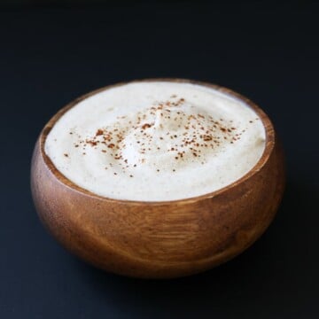 A small wooden bowl filled with a chili lime sauce and dusted with chili powder