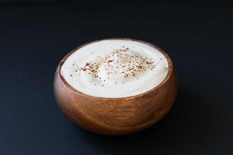 A small wooden bowl filled with a chili lime sauce and dusted with chili powder