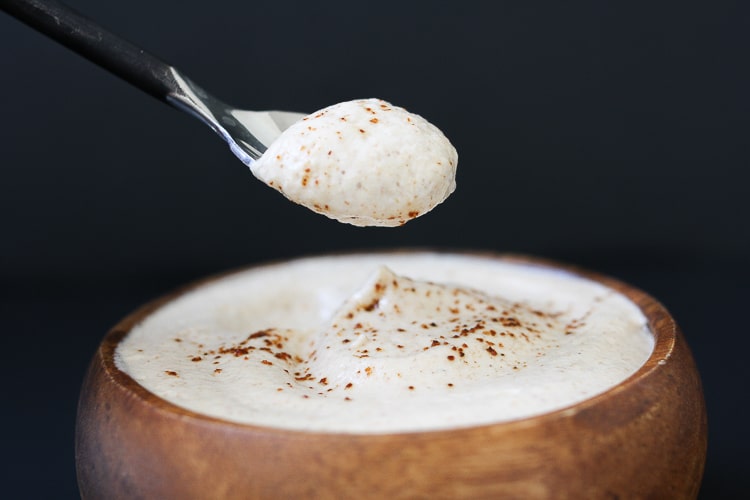 A spoon scooping up some creamy lime sauce from a wooden bowl