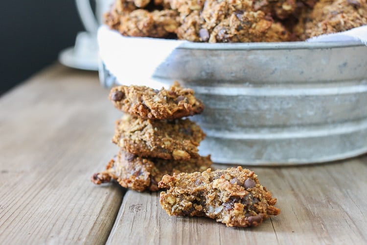 A side shot of chocolate chip oat cookies in a pile sitting on a wooden surface