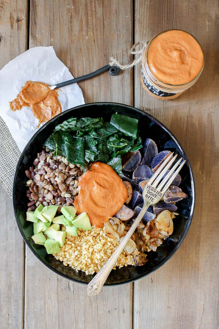 An overhead shot of a barbecue tahini power bowl in a black bowl with a fork