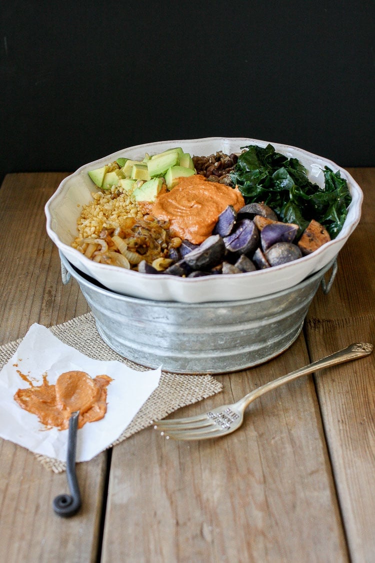 Barbecue Tahini power bowl with spinach, swiss chard or kale and potatoes sitting on a wooden surface with a fork