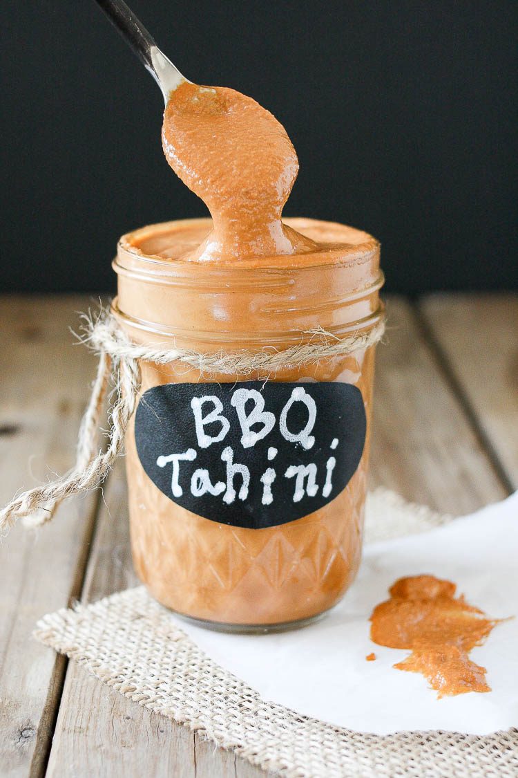 Barbecue tahini sauce in a glass jar with a spoon scooping some out of the jar