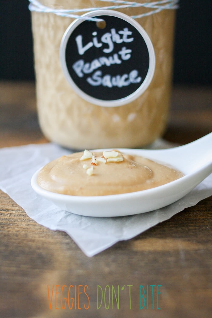 A close up of a spoon of Peanut Sauce and a jar of the sauce in the background