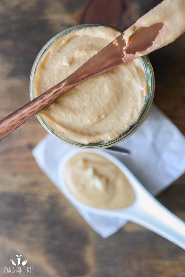 An overhead shot of Peanut Sauce in a jar with a knife on top
