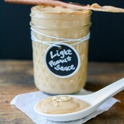 A jar of peanut sauce sitting on a wooden surface