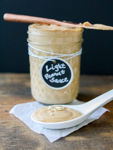 A jar of peanut sauce sitting on a wooden surface