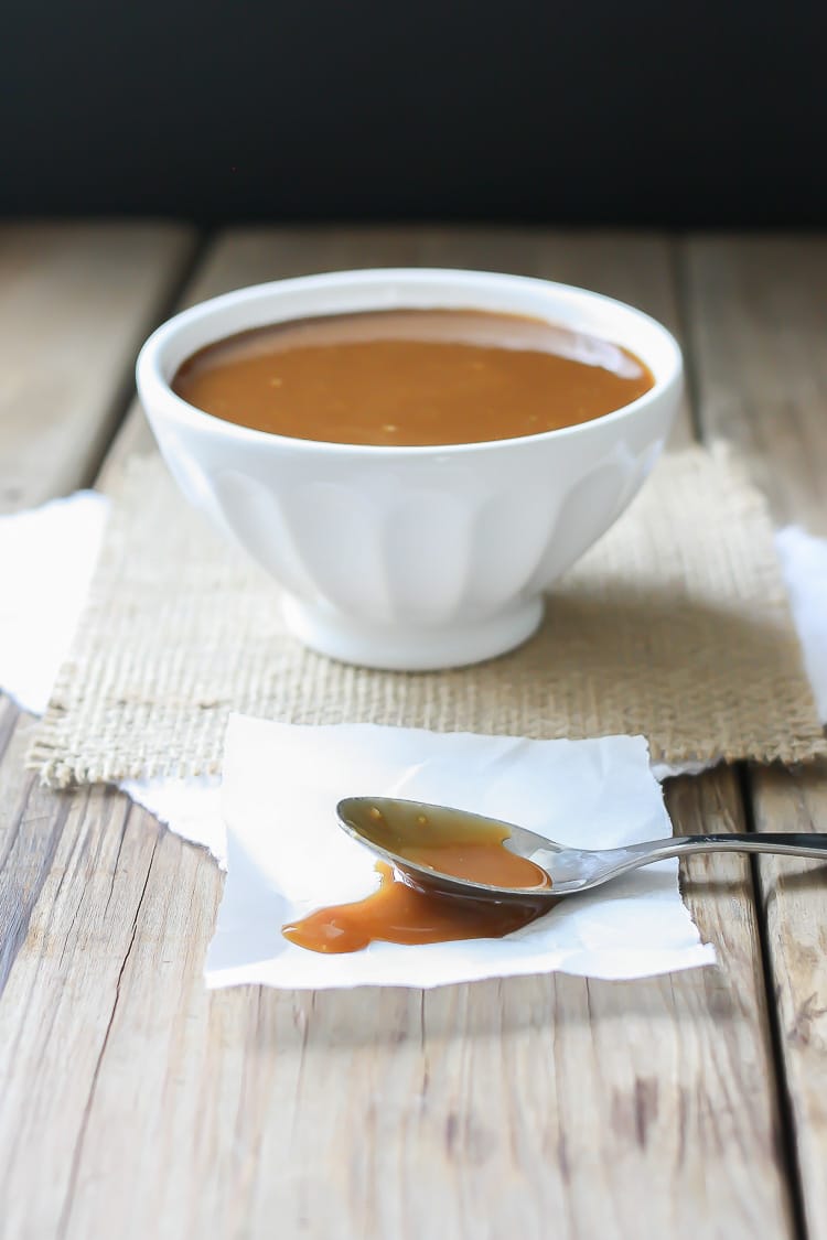 A side shot of Maple Miso Balsamic Sauce in a white bowl with a spoon at the side