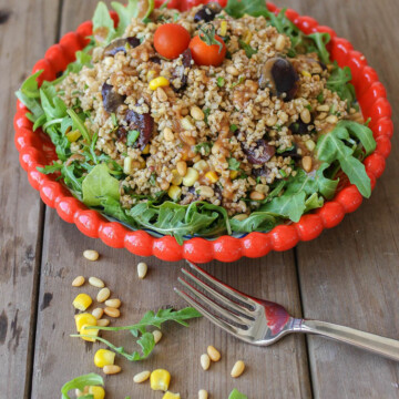 A vegan arugula salad on a white plate with a fork