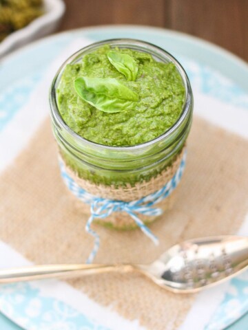 Vegan Spinach Pesto in a glass jar topped with basil leaves