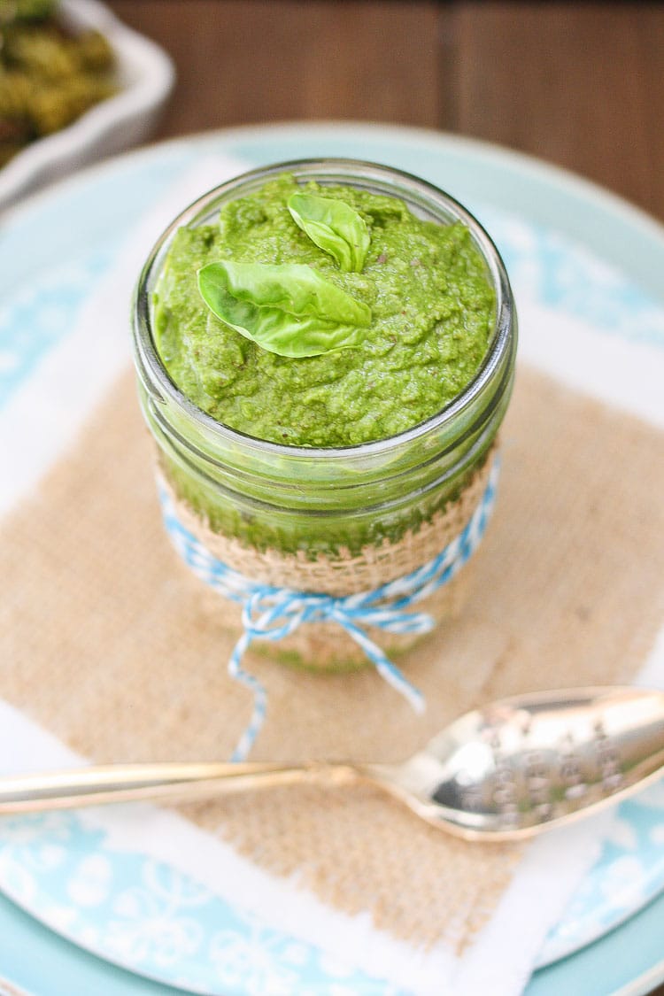 Vegan Spinach Pesto in a glass jar topped with basil leaves