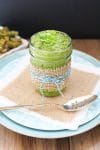 Vegan Spinach Pesto with Tahini in a glass jar with a spoon at the side