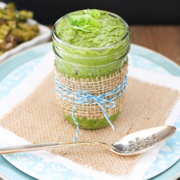 Vegan Spinach Pesto with Tahini in a glass jar with a spoon at the side