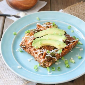 Vegan Enchilada Noodles Casserole on a blue plate topped with slices of avocado