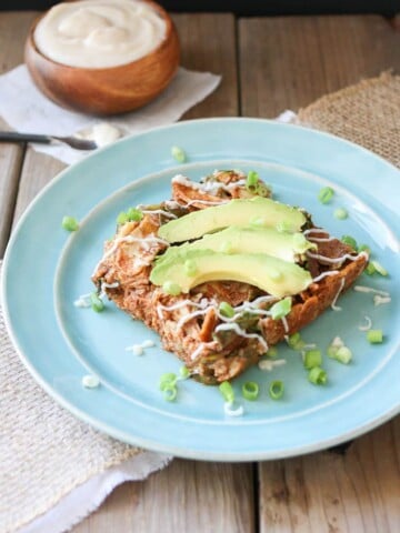 Vegan Enchilada Noodles Casserole on a blue plate topped with slices of avocado