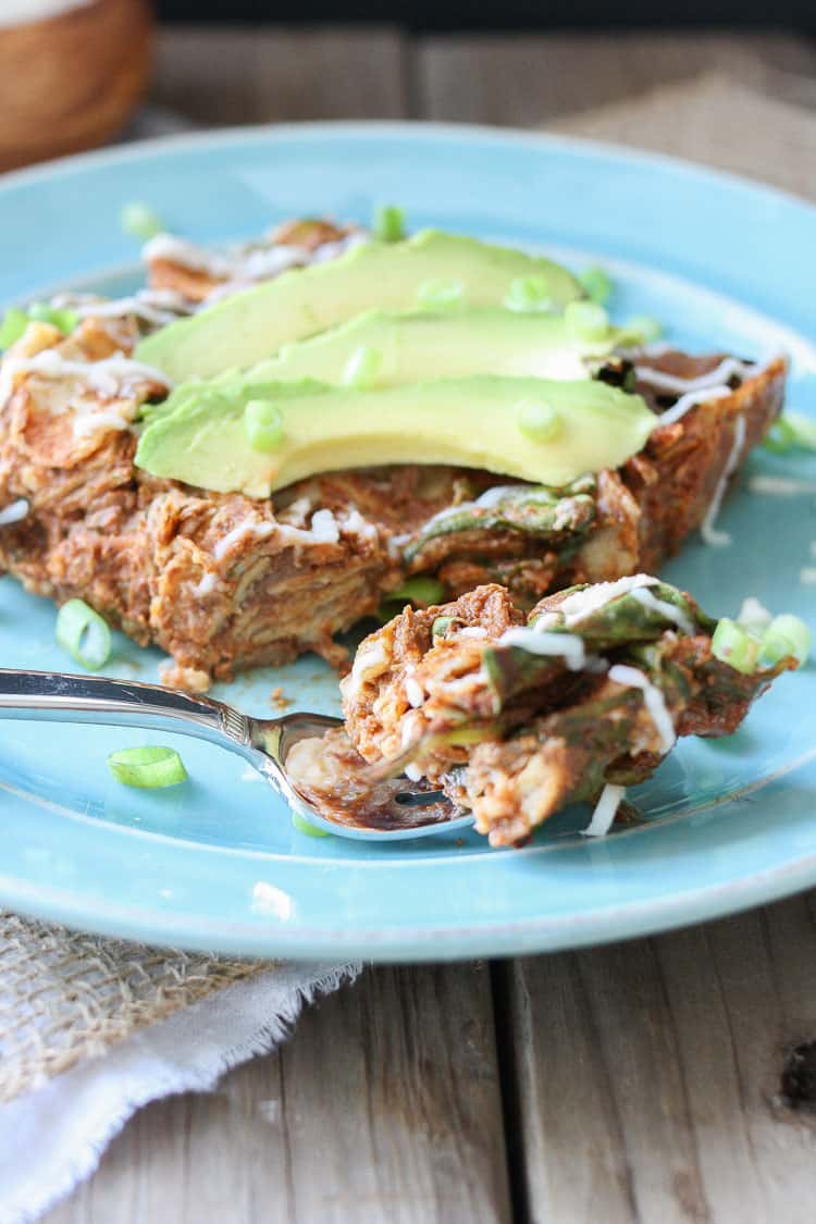 Enchilada Noodles casserole on a blue plate topped with avocado