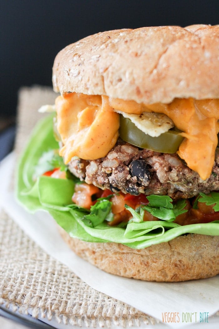 A side shot of a Mexican nacho burger with oozing vegan cheese sauce