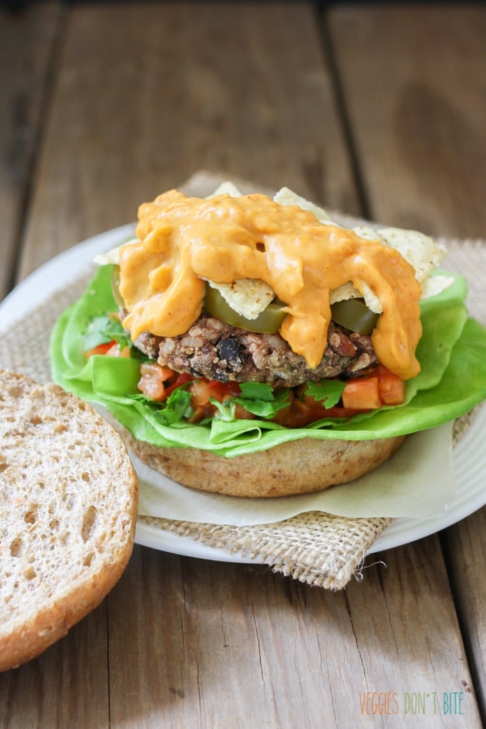 A close up of a Mexican nacho burger topped with vegan cheese sauce