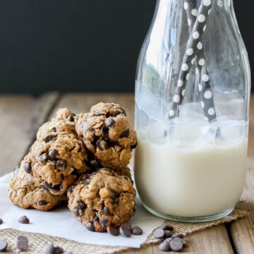 A small pile of Cookie Dough Balls‬‬‬‬‬‬‬‬‬‬‬ next to a glass of milk with straws