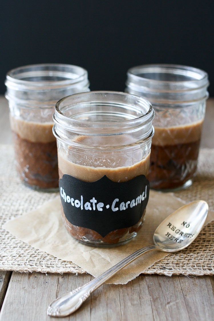 Three jars of chocolate protein pudding sitting on a wooden surface with a spoon