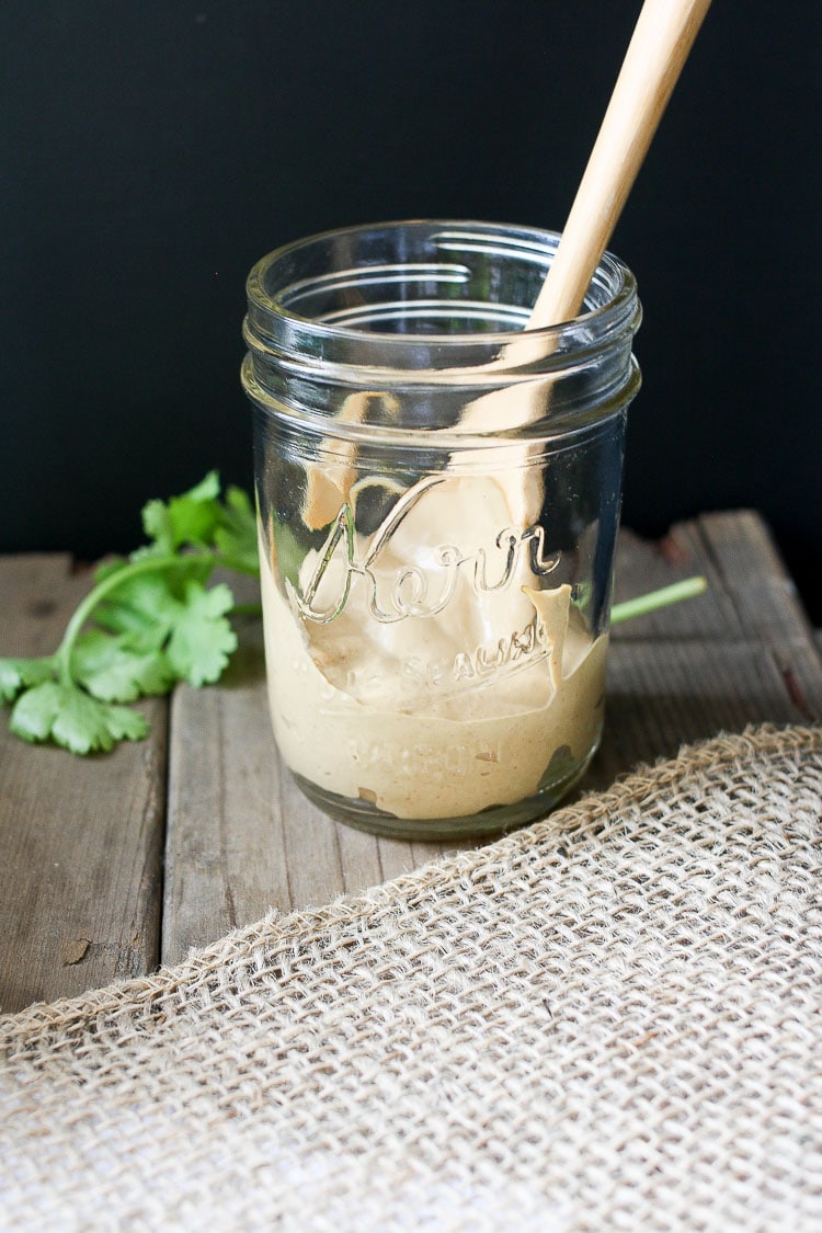 A mason jar filled with a vegan cream taco sauce sitting on a wooden surface