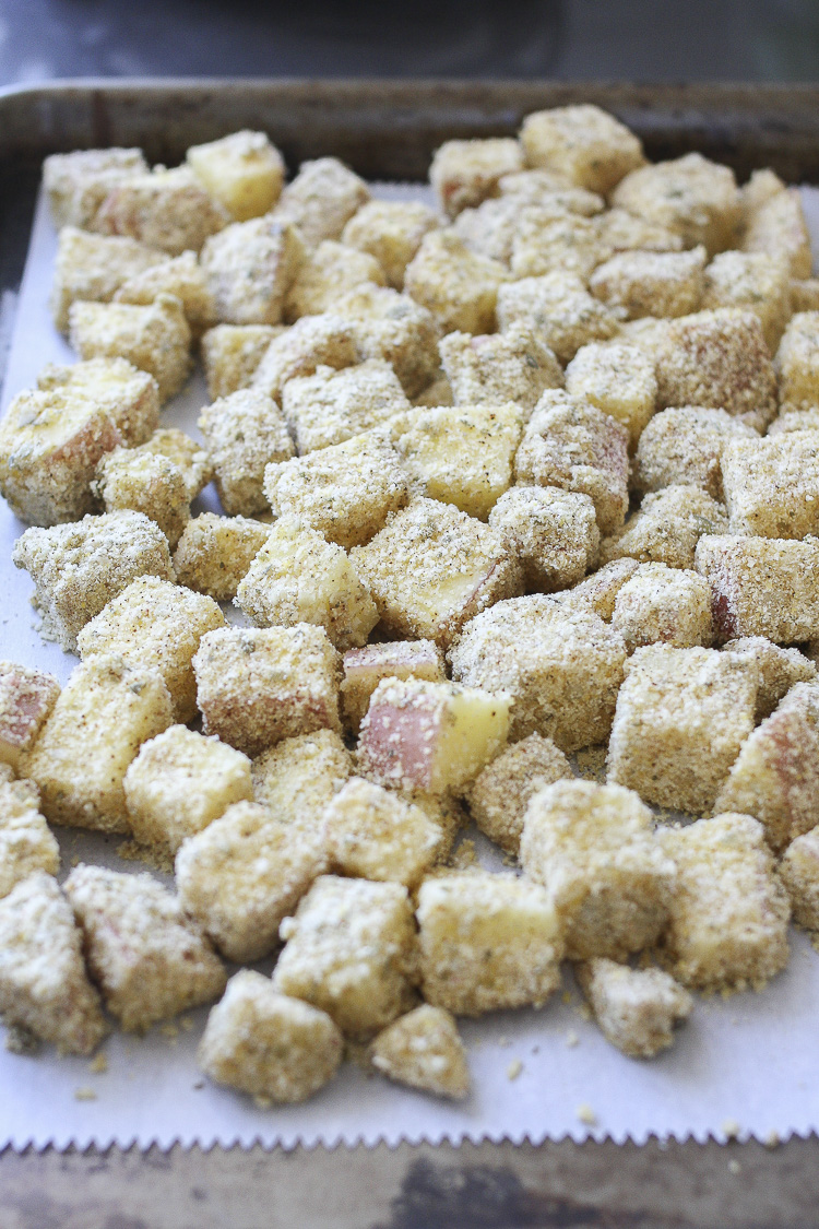 Parchment paper on a tray filled with crispy baked squares of potato