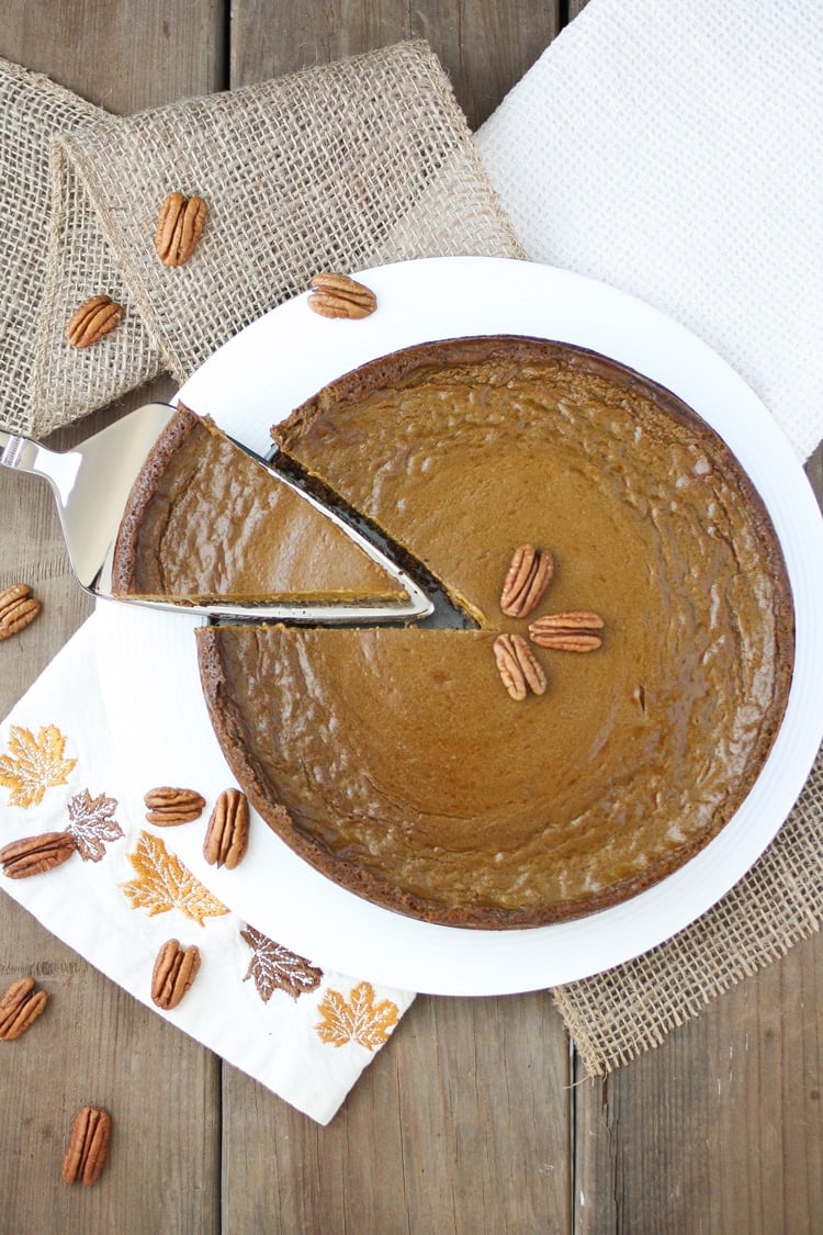 Top view of a cake knife removing a piece of pumpkin pie with pecan crust