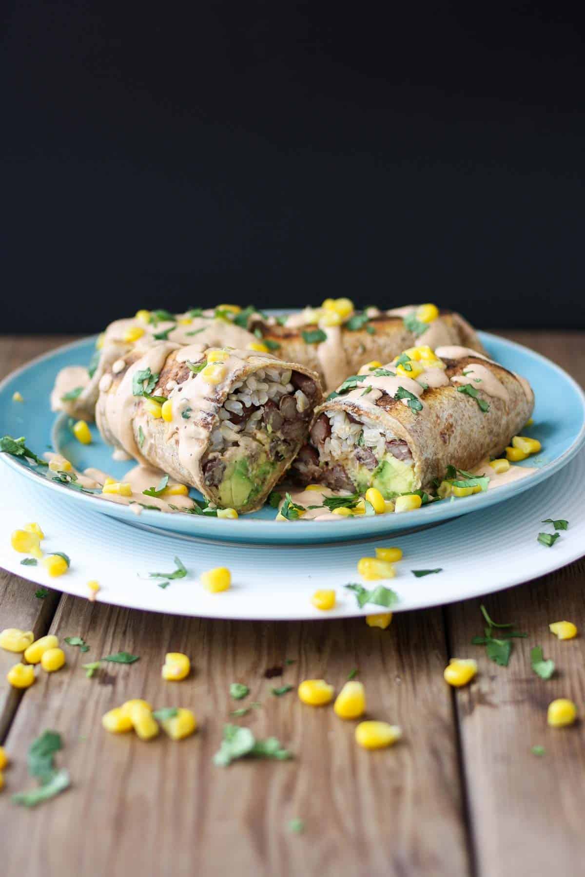 Vegan grilled burritos cut in half and sitting on a blue plate