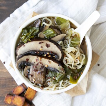 White bowl filled with miso soup, bok choy, portobello mushrooms and noodles