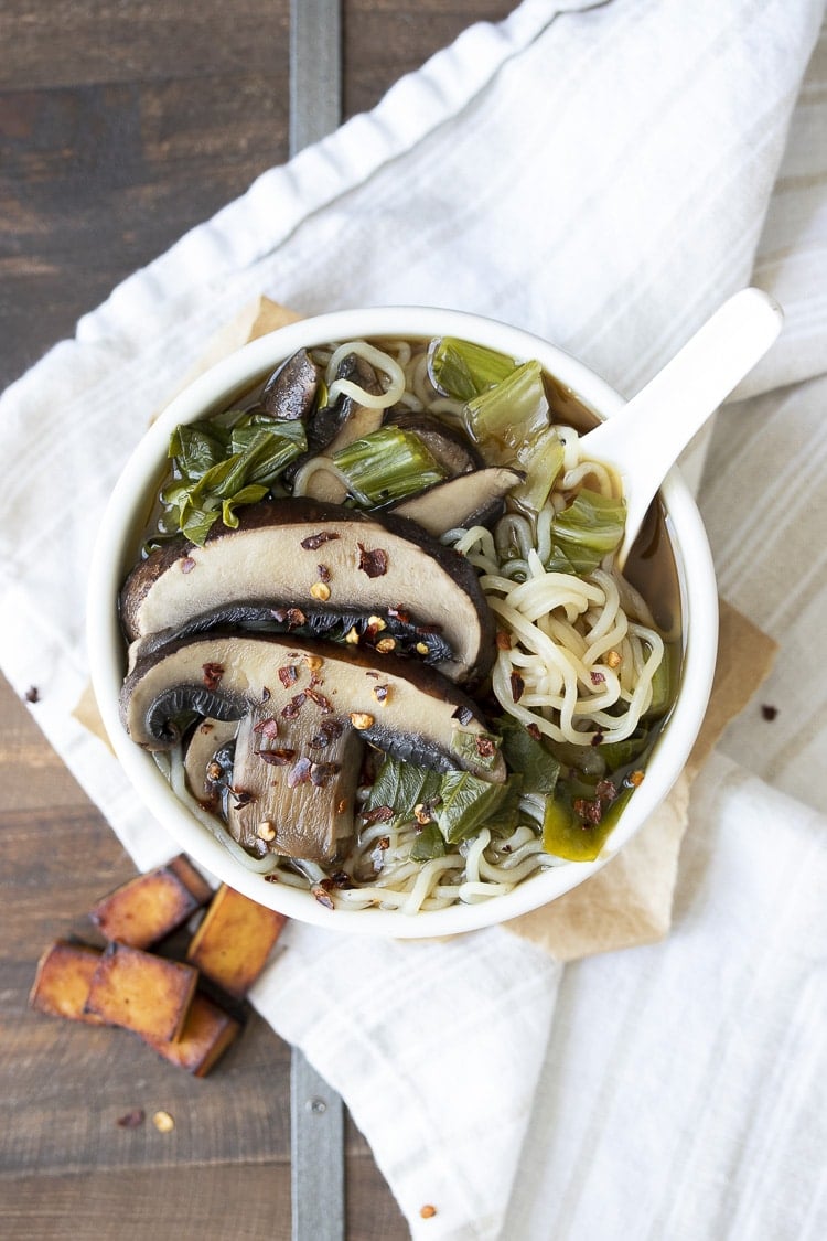 White bowl filled with miso soup, bok choy, portobello mushrooms and noodles