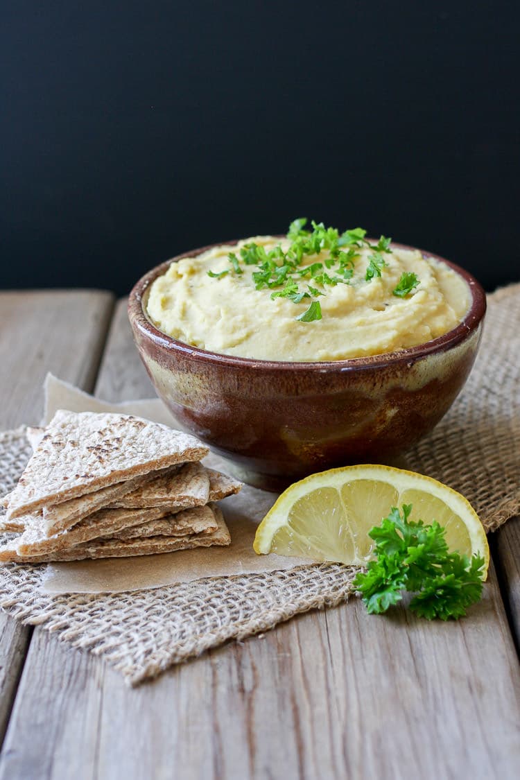 Yellow split pea dip in a small bowl with pita bread at the side