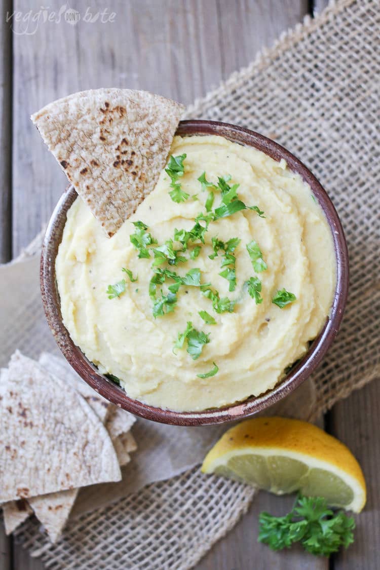 An overhead shot of a Yellow split pea dip with pita bread chips and a lemon wedge