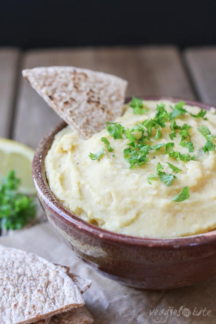 A close up of a Yellow split pea dip with pita bread sitting in it