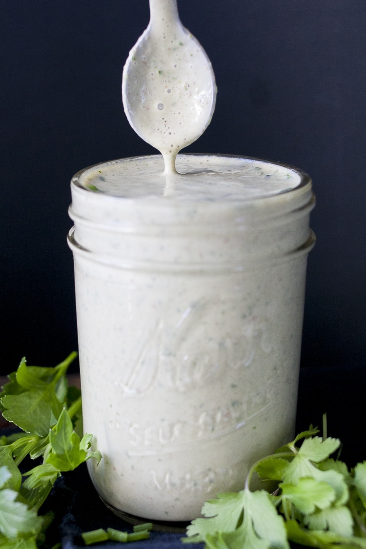 Spoon coming out of a glass jar filled with creamy white sauce