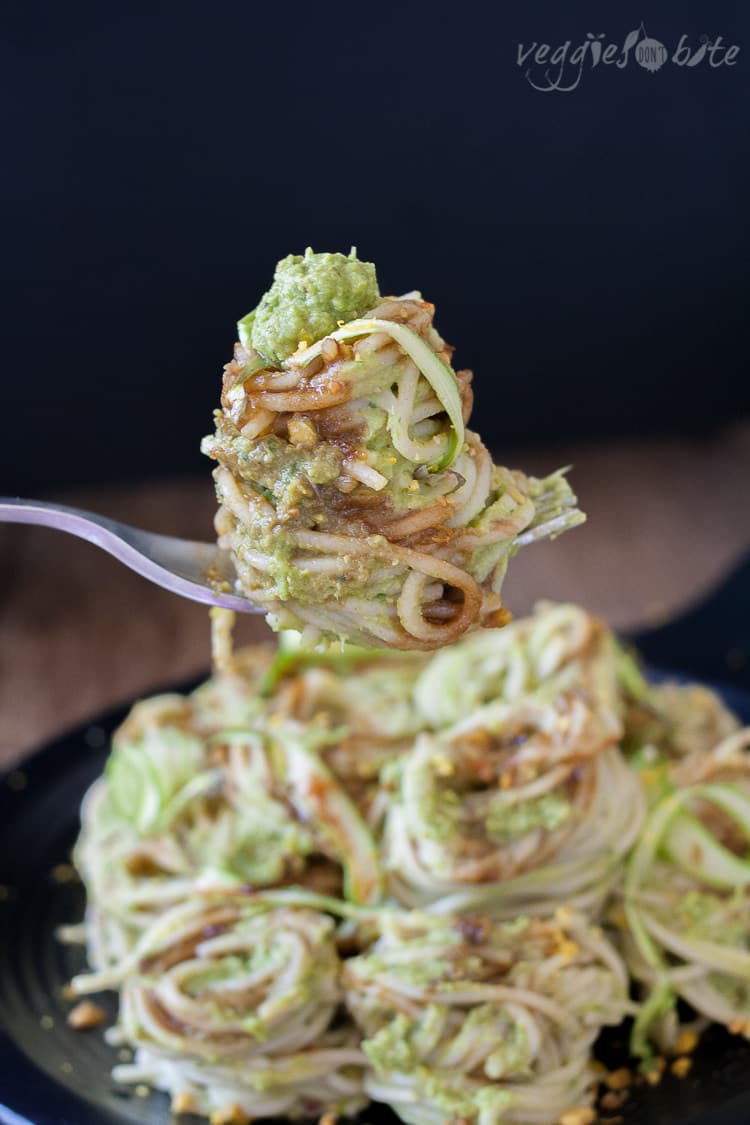 A fork picking up a bite of pasta covered in asparagus pesto 