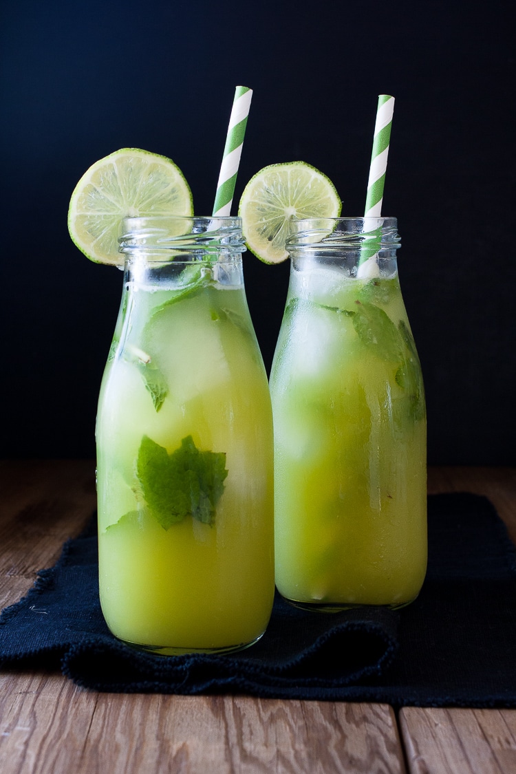 Fresh anti-inflammatory juice in two bottles with straws on a wooden surface