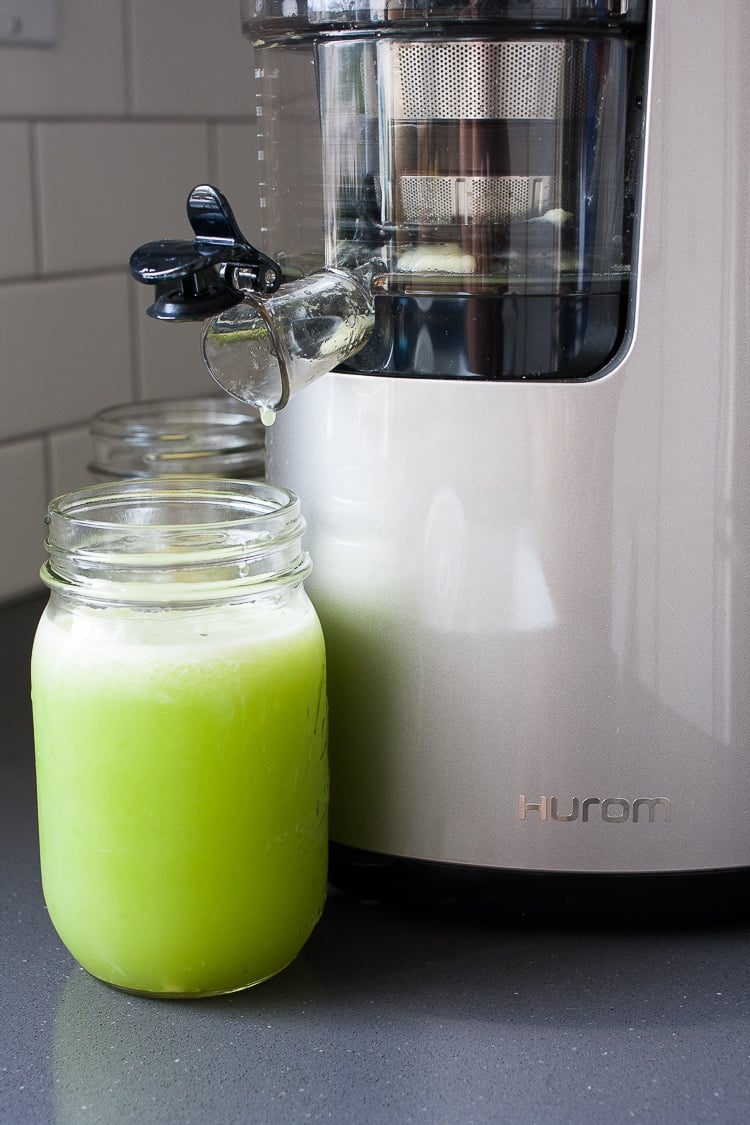 Fresh anti-inflammatory juice coming out a juicer and filling a glass