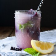 Blueberry mint lemonade in a mason jar with a lemon wedge at the side