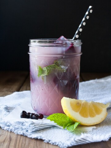 Blueberry mint lemonade in a mason jar with a lemon wedge at the side