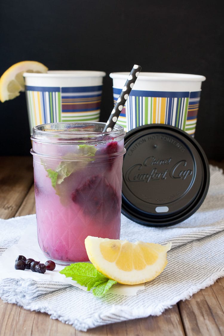 A mason jar with blueberry mint lemonade and a black straw