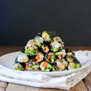 vegan sushi rolls stacked on a white plate