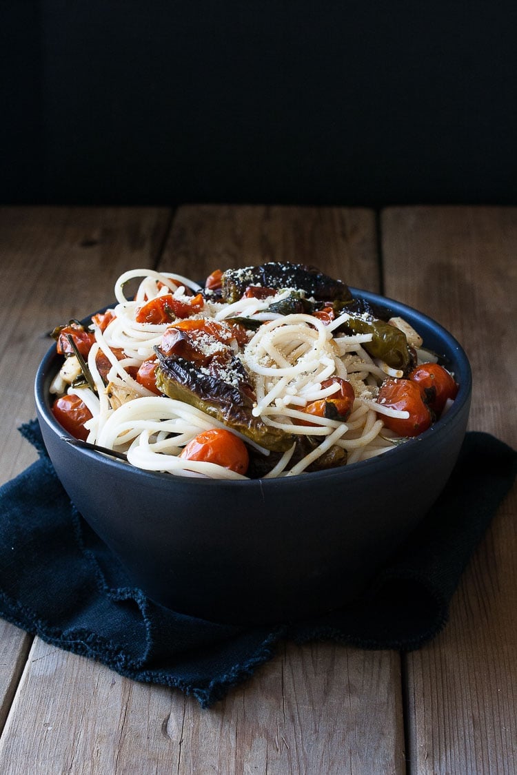 A bowl of spaghetti with charred tomatoes and peppers